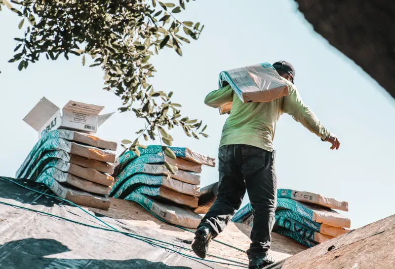 Roofer is carrying shingles ready to install.