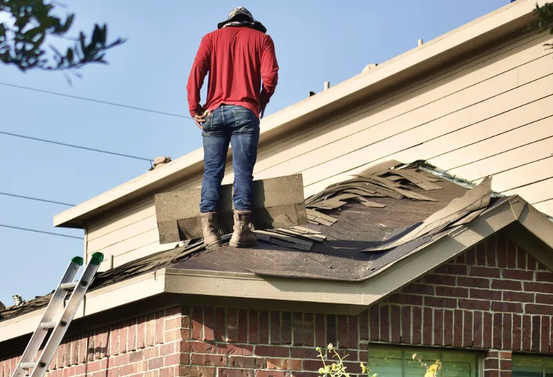 Roofer is removing dammaged shingles before replacing them with new roofing.
